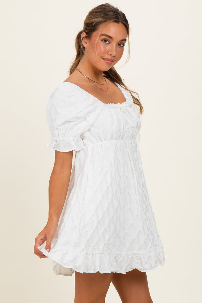 woman wearing a white short sleeve mini dress with a square neckline and textured fabric