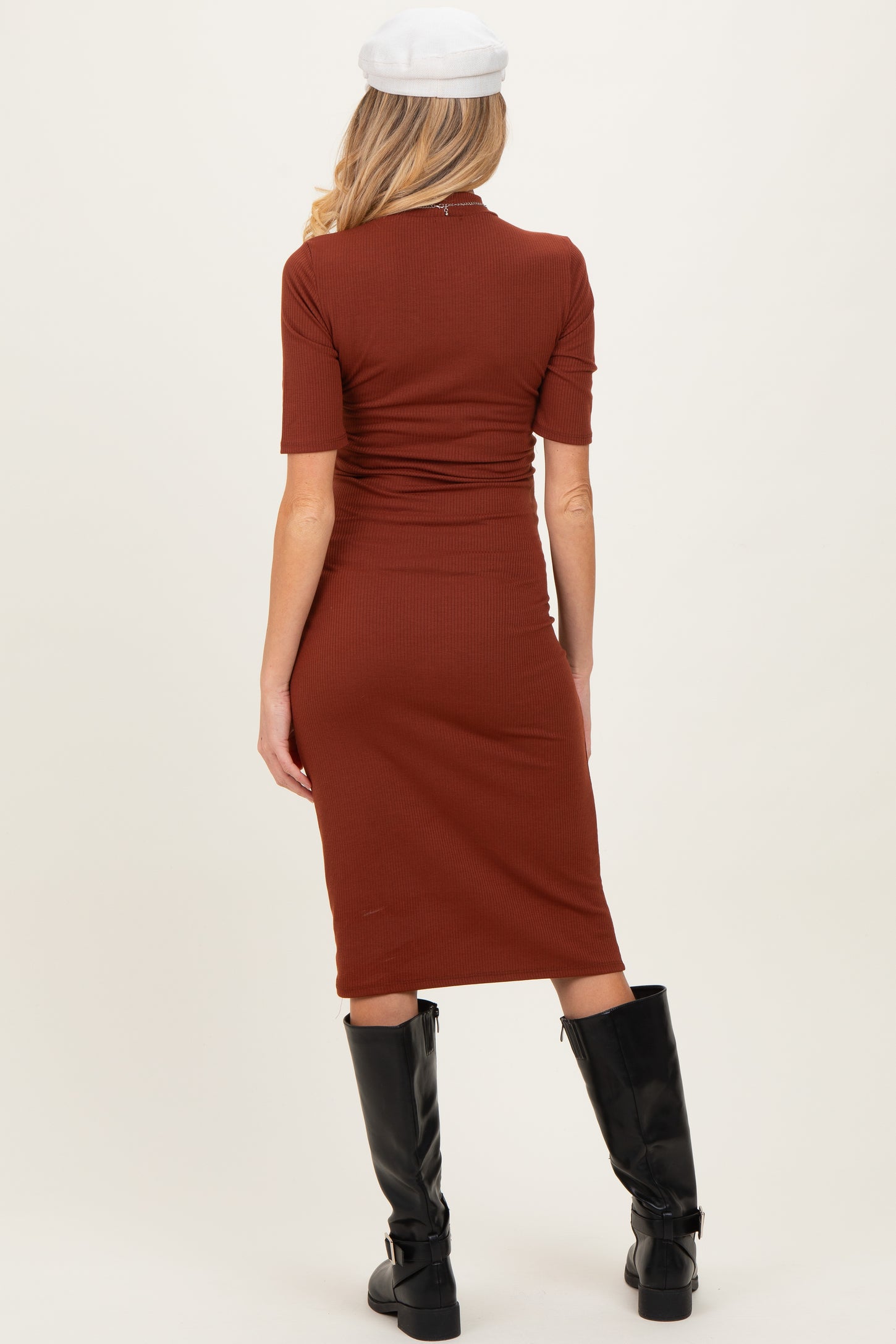 woman wearing a back view of a rust-colored fitted maternity dress with short sleeves and a knee-length hem
