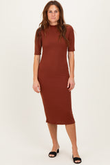 woman wearing a rust-colored ribbed midi dress with short sleeves and standing in black heeled sandals