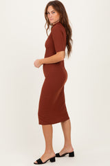 woman wearing a rust ribbed midi dress with short sleeves and a fitted silhouette, styled with black slide sandals