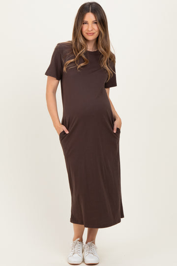 woman wearing a dark brown short sleeve maternity dress with pockets and a visible baby bump