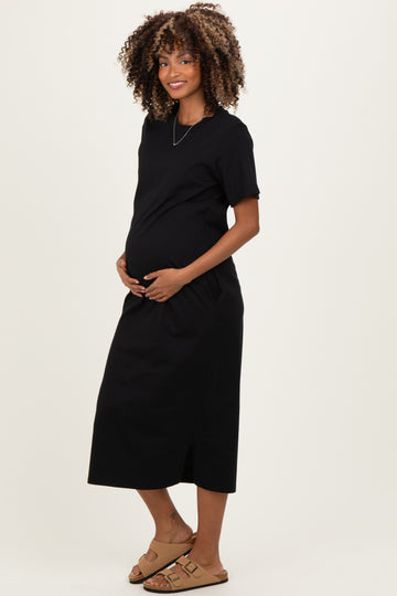 woman wearing a black maternity dress with short sleeves and side pockets, showcasing her baby bump