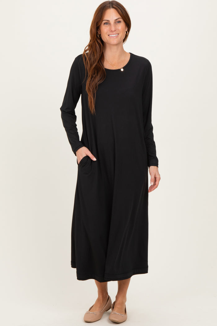 woman wearing a black long sleeve maxi dress with a round neckline and side pockets