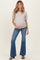 woman wearing a light gray short sleeve maternity top and blue flared maternity jeans, holding her baby bump