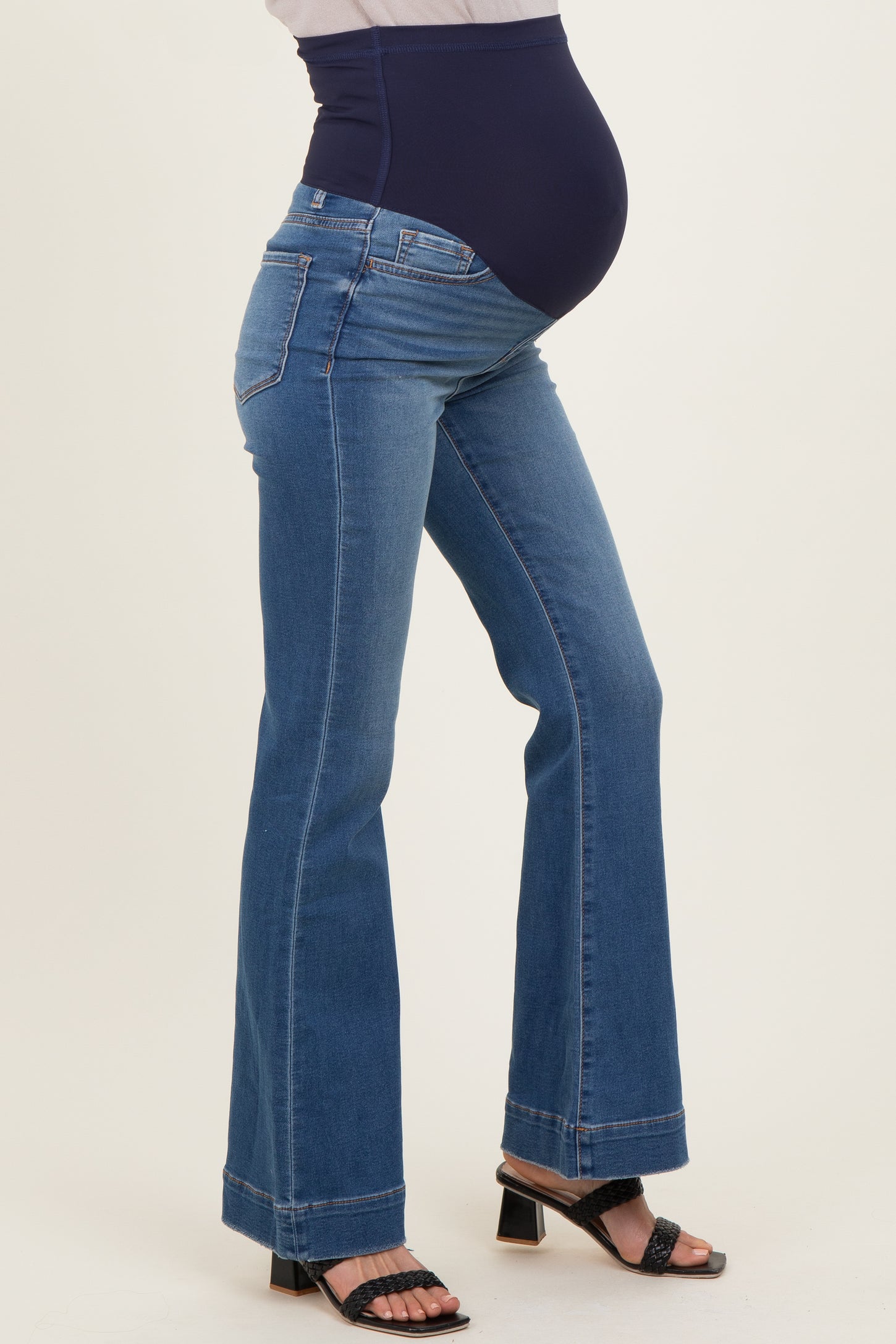 woman wearing blue maternity bootcut jeans with a navy belly panel and showing her baby bump