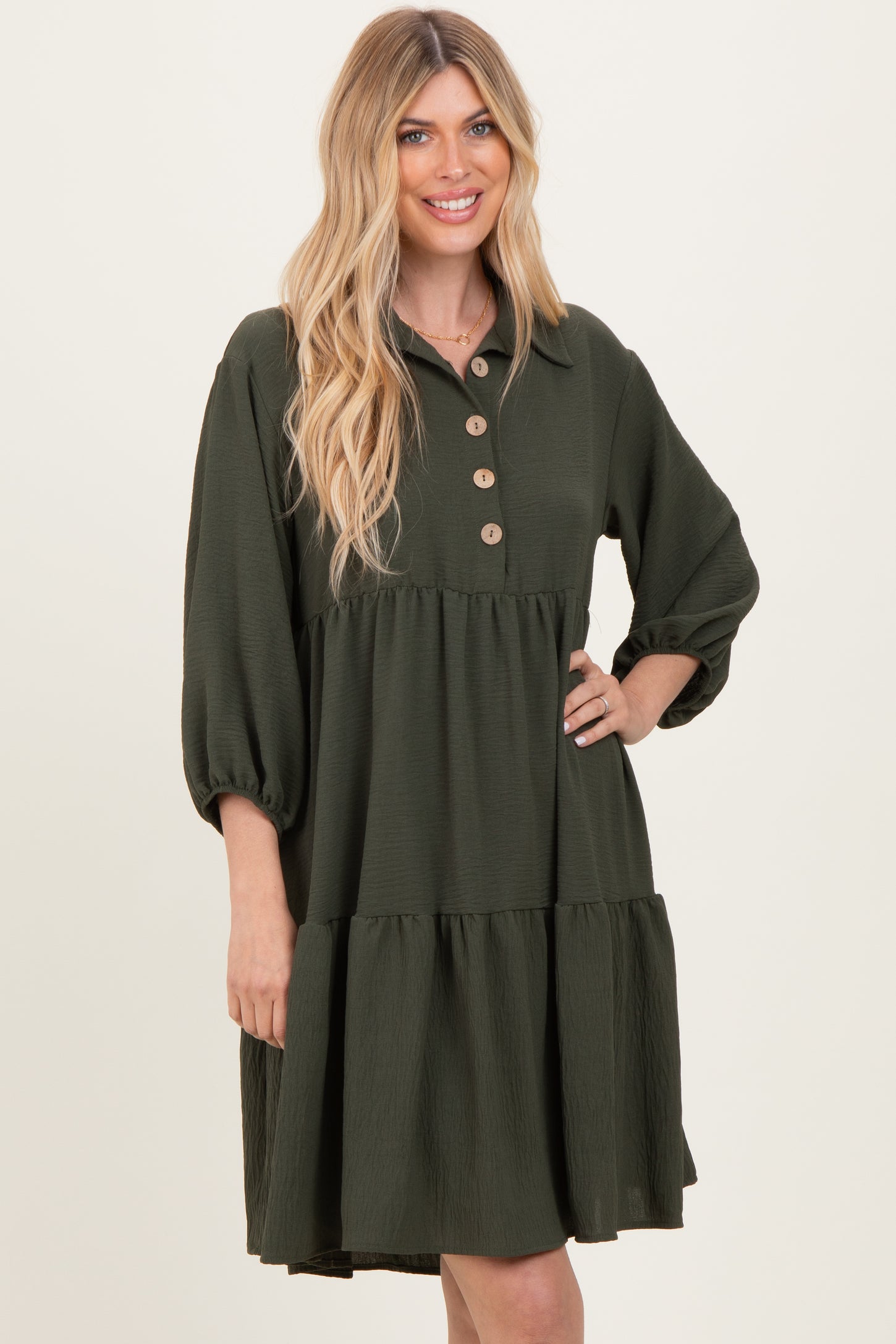 woman wearing a dark green tiered shirtdress with button details and puff sleeves