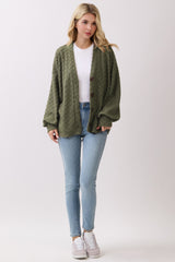 woman wearing a green textured cardigan over a white t-shirt and blue skinny jeans