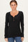 woman wearing a black ribbed long sleeve henley top with button details and paired with blue jeans