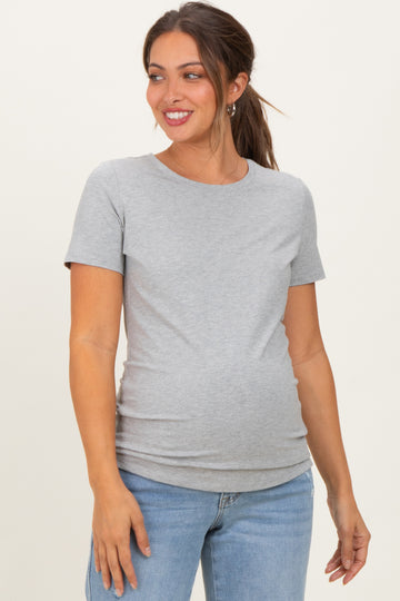 woman wearing a light grey maternity t-shirt and showing her baby bump while smiling