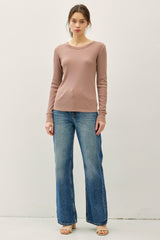woman wearing a light pink long sleeve top paired with wide leg blue jeans