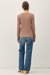 woman wearing a brown long sleeve top with a scoop neckline and relaxed fit paired with light blue wide-leg jeans