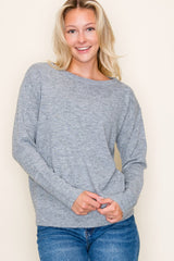 woman wearing a gray long sleeve sweater with a relaxed fit and light blue jeans