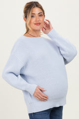 woman wearing a light blue oversized maternity sweater and holding her baby bump