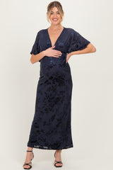 woman wearing a navy floral maternity gown with a deep v-neckline and short sleeves, holding her baby bump