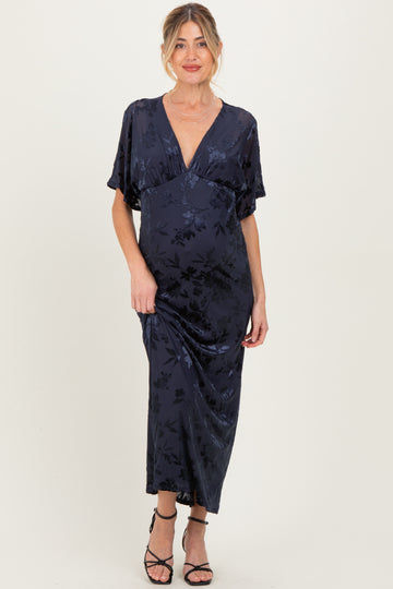 woman wearing a navy floral maternity maxi dress with a deep V-neckline and flutter sleeves, showing her baby bump