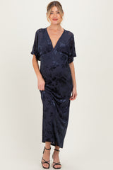 woman wearing a navy floral maternity maxi dress with a deep V-neckline and flutter sleeves, showing her baby bump