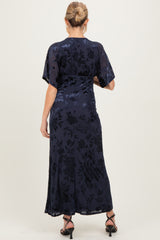 woman wearing a navy floral print maternity maxi dress with short flutter sleeves and a fitted waist, viewed from the back