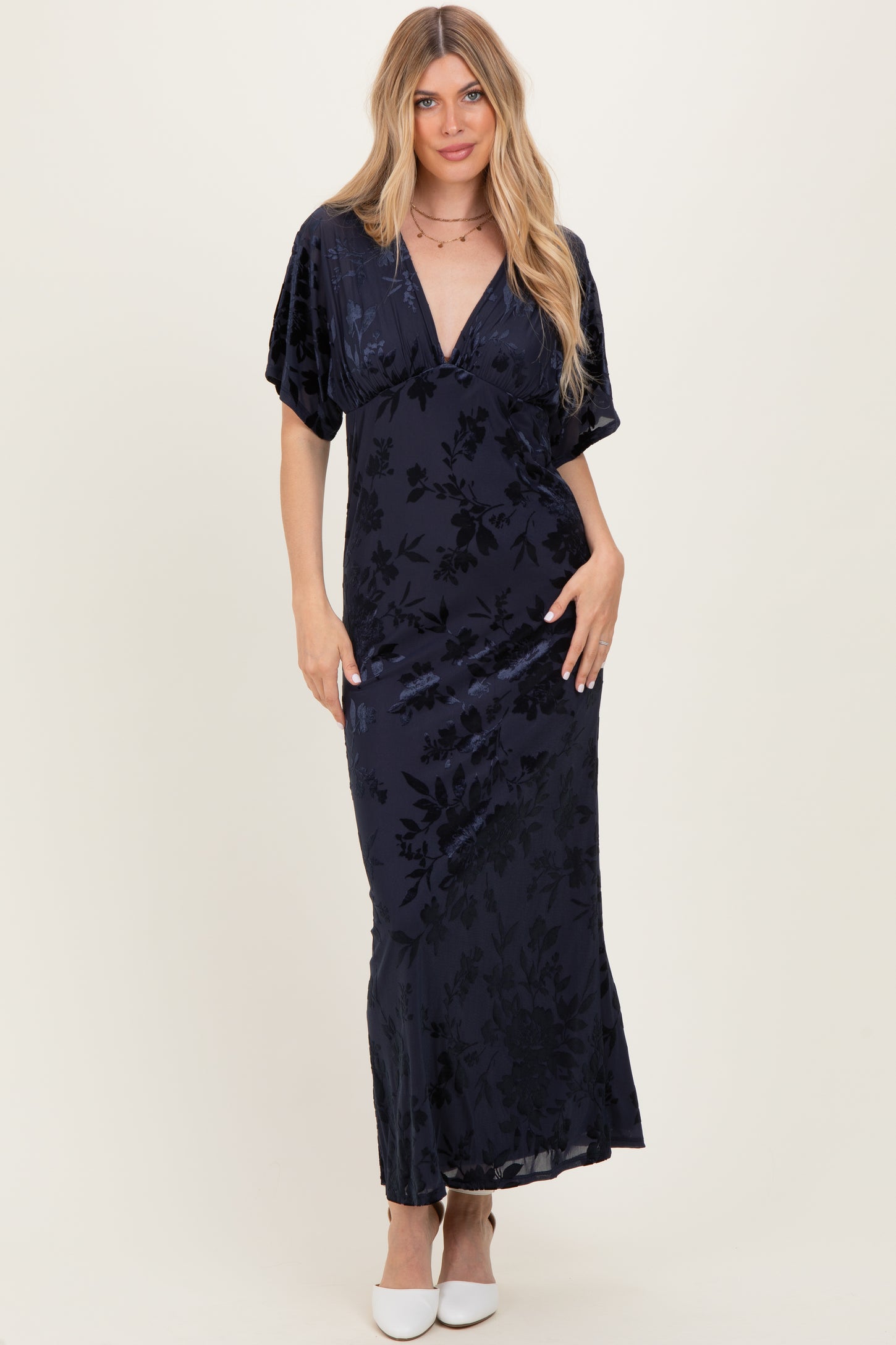 woman wearing a dark navy floral velvet maxi dress with short sleeves and a deep v-neckline