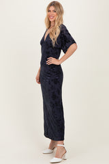 woman wearing a navy floral maxi dress with a deep v-neck and short sleeves, posing sideways