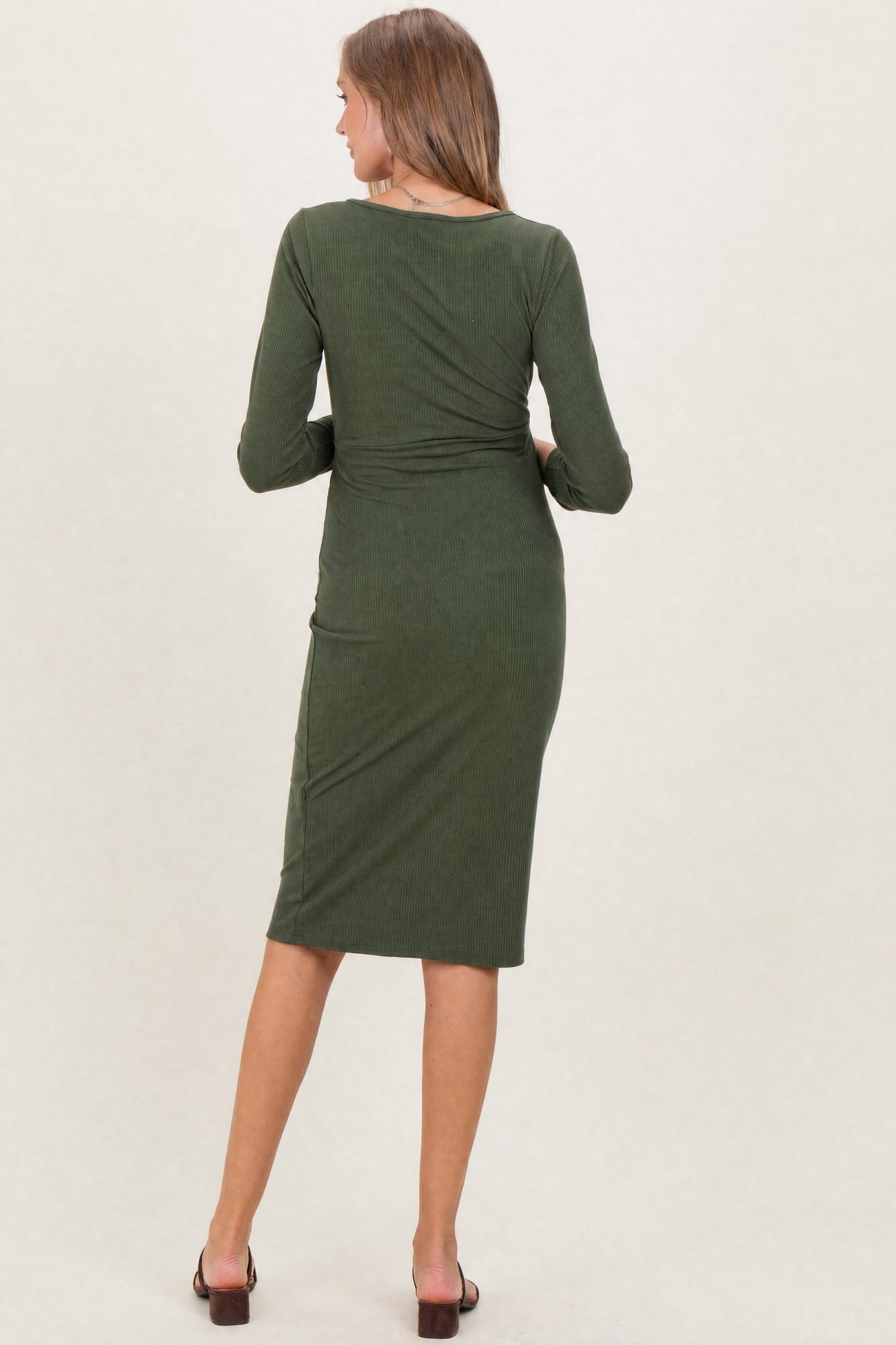 woman wearing a dark green long sleeve maternity dress, showcasing a fitted silhouette and knee-length hem