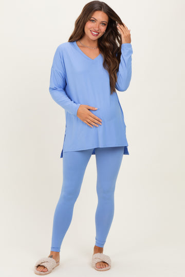 woman wearing a light blue maternity top and matching leggings, holding her baby bump