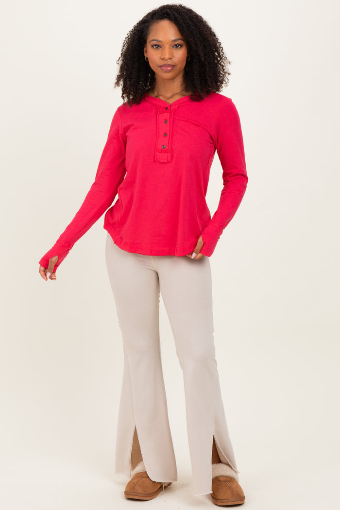 woman wearing a bright pink long sleeve henley top and beige flared pants