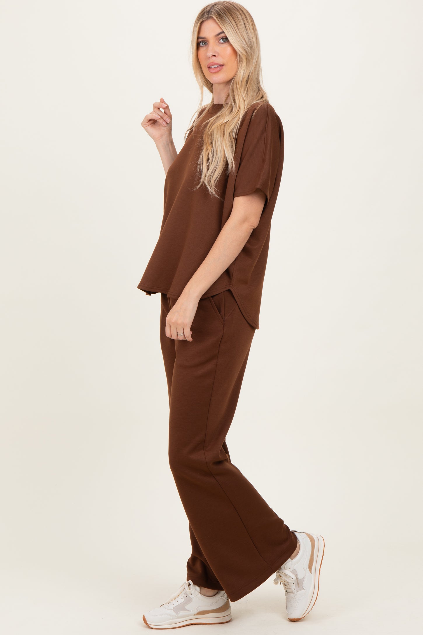 woman wearing a brown relaxed fit short sleeve top and matching wide leg pants with white sneakers