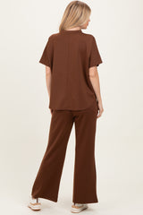 woman wearing a brown short sleeve top and matching wide-leg pants, viewed from the back