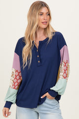 woman wearing a navy blue ribbed top with colorful patterned sleeves and buttons at the neckline