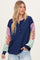 woman wearing a navy blue ribbed top with colorful patterned sleeves and buttons at the neckline