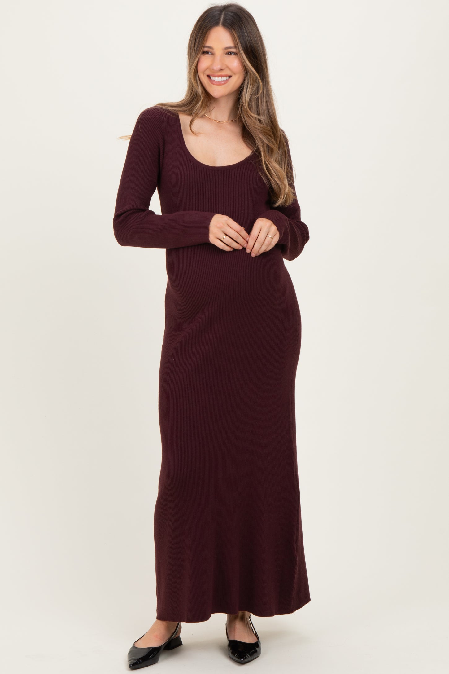 woman wearing a burgundy long sleeve ribbed maternity dress with a scoop neckline and visible baby bump