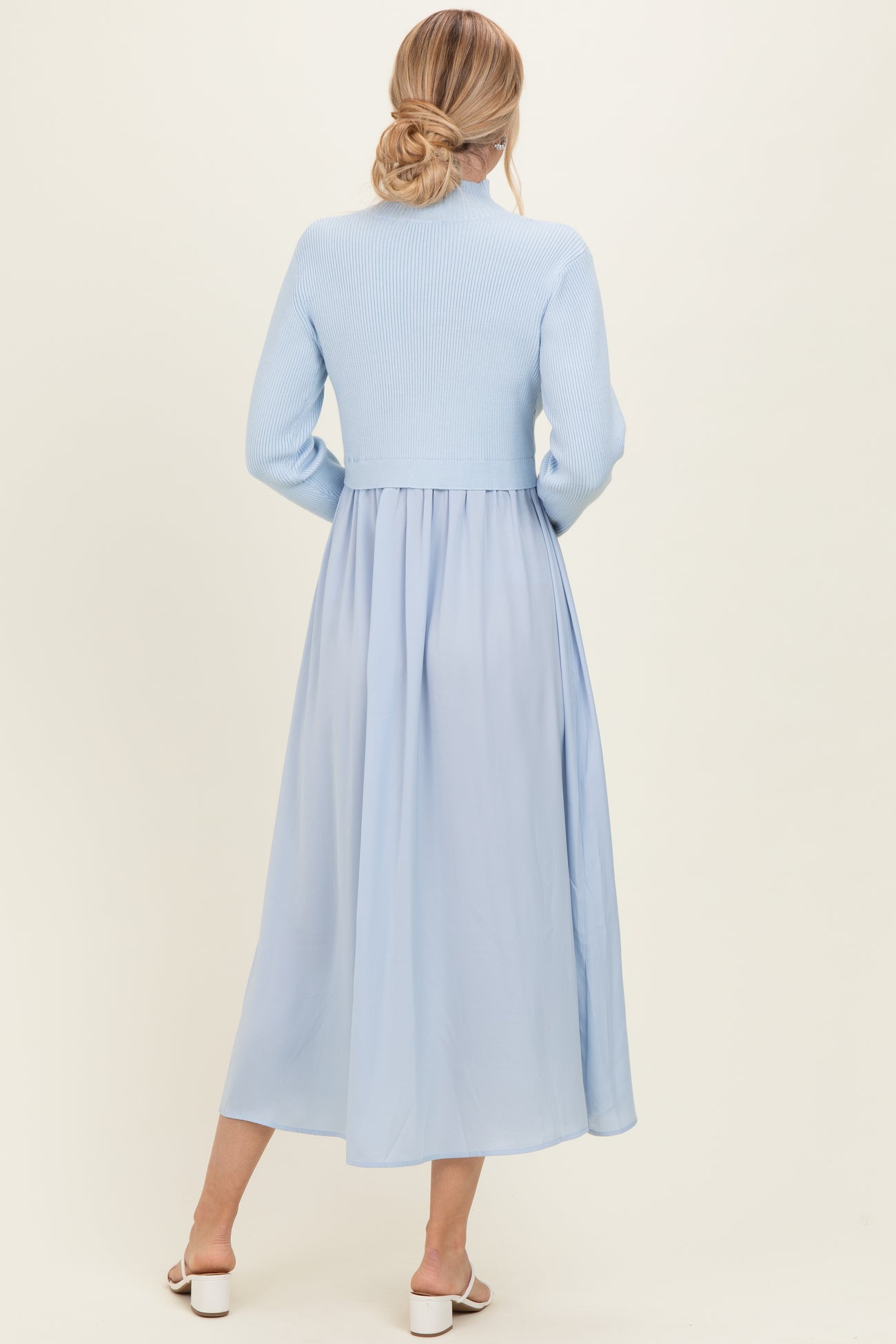 woman wearing a light blue ribbed knit long sleeve dress with a flowing chiffon skirt, viewed from the back