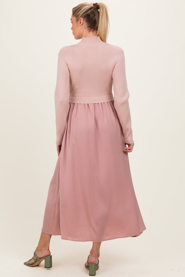 woman wearing a pink maternity dress with a ribbed top and flowing skirt, showing her back and styled with green heels
