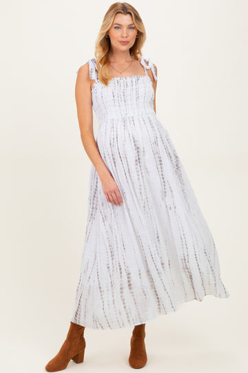 woman wearing a white and brown tie-dye maternity dress with smocked bodice and tie straps, showing her baby bump