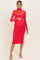 woman wearing a red maternity dress with a sheer turtleneck and long sleeves, holding her baby bump