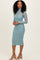 woman wearing a light blue long sleeve form-fitting midi dress with a sheer neck detail and light pink heels
