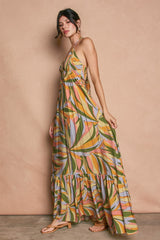 woman wearing a colorful leaf print maxi dress with a tiered skirt and adjustable straps