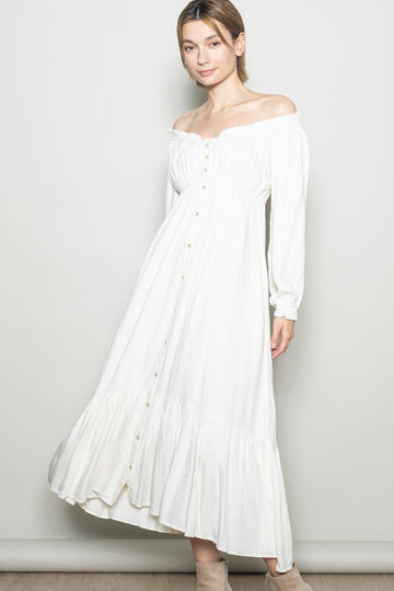 woman wearing a white off-the-shoulder button-up maxi dress with long sleeves and a ruffled hem