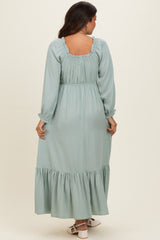 woman wearing a mint green long sleeve maternity maxi dress with ruffled details and a fitted waist