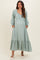 woman wearing a light green maternity maxi dress with button details and pockets, featuring a ruffled hem and long sleeves, showing her baby bump
