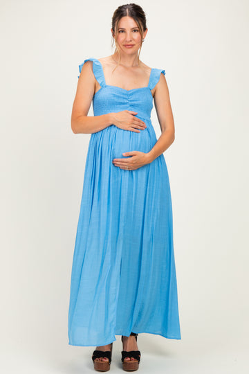 woman wearing a light blue maternity maxi dress with ruffled straps and holding her baby bump