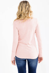 woman wearing a light pink long sleeve top, view from the back, paired with blue jeans
