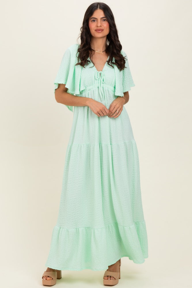 woman wearing a mint green tiered maxi dress with short flutter sleeves and a tie-front detail