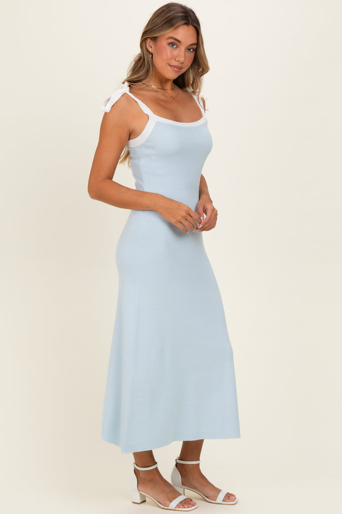 woman wearing a light blue ribbed midi dress with white straps and tie details, styled with white strappy sandals
