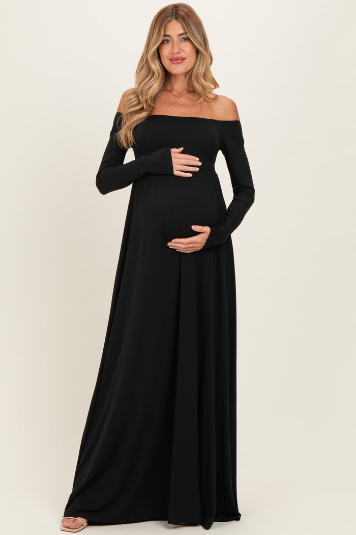 woman wearing a black off-the-shoulder maternity dress and showing her baby bump