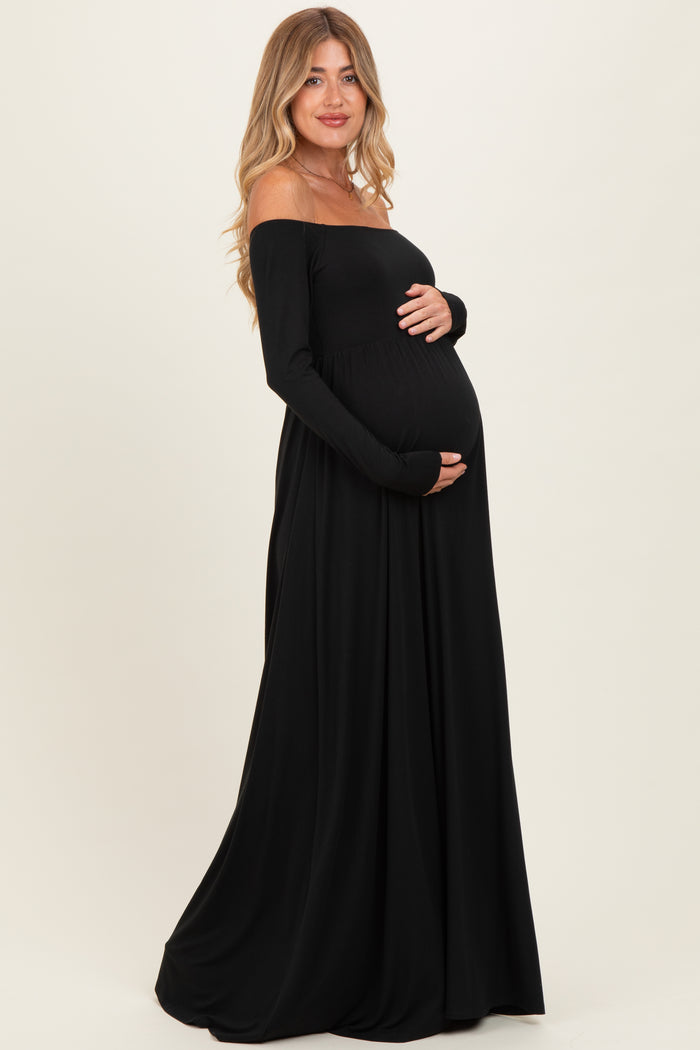 woman wearing a black off-shoulder maternity gown and holding her baby bump