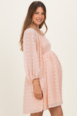 woman wearing a blush pink maternity dress with balloon sleeves and a smocked bodice, showing her baby bump