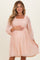 woman wearing a soft pink maternity dress with dot details and puff sleeves, holding her baby bump