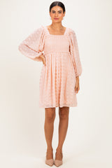 woman wearing a light pink smocked mini dress with puff sleeves and textured dots