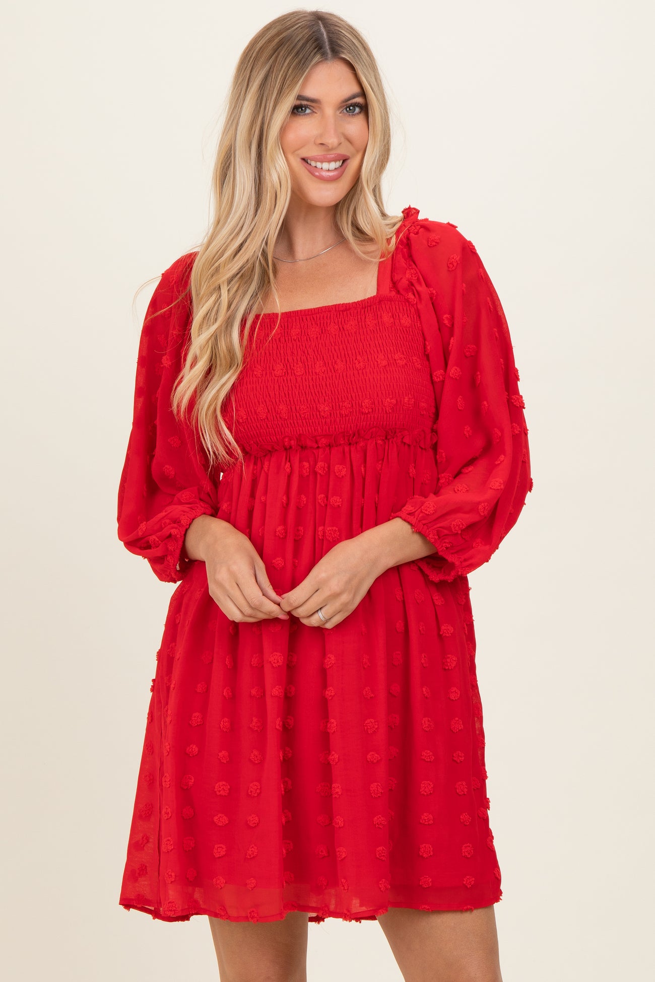 woman wearing a red smocked mini dress with puff sleeves and floral pattern details